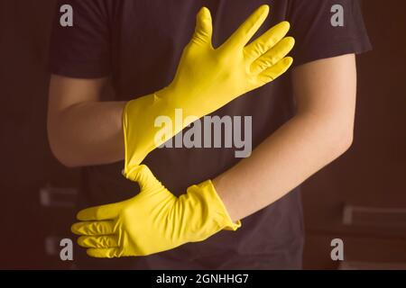 Una donna in guanti di gomma gialla fa il lavoro domestico Foto Stock