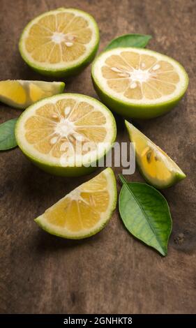 arance dolci, fette di frutta con foglie verdi sul piano del tavolo in legno, fondo con spazio copia Foto Stock