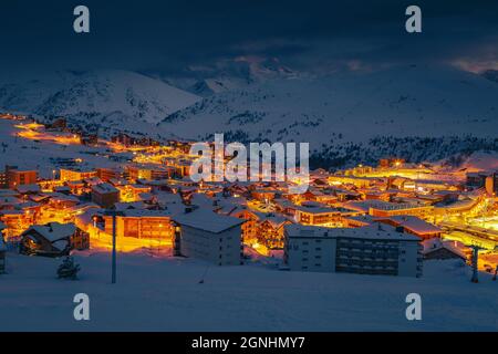 Favolosa stazione sciistica invernale e paesaggio urbano di notte. Famosa destinazione di viaggio e piste nevose di notte, Alpe d Huez, Rodano Alpi, Francia, Europa Foto Stock