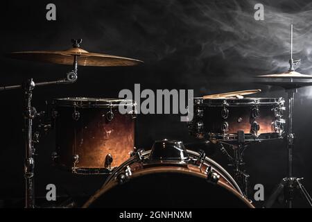 Parte di un drum kit su sfondo nero, percussione strumento, tamburo snare, basso tamburo, hi-Hat sul palco sotto i riflettori. Foto Stock