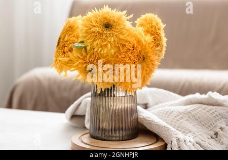 Un bouquet di girasoli luminosi in vaso di vetro su sfondo sfocato all'interno della stanza. Foto Stock