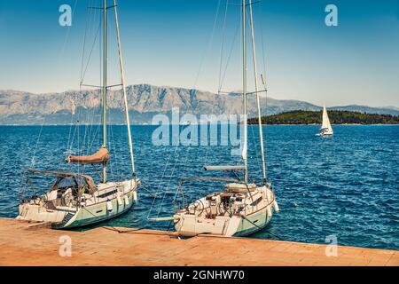 Splendida vista mattutina del piccolo porto del villaggio di Perigiali con due yacht di lusso. Colorato mare di primavera del Mar Ionio. Scena all'aperto di Lefk Foto Stock