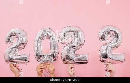Felice anno nuovo 2022 celebrazione. Palloncini in lamina d'argento numero 2022 su sfondo rosa. Foto Stock