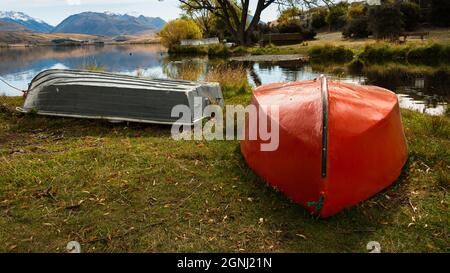 Barche a remi rosse e grigie sulla riva del lago Alexandrina in autunno, Mackenzie Country, Canterbury, Nuova Zelanda. Foto Stock