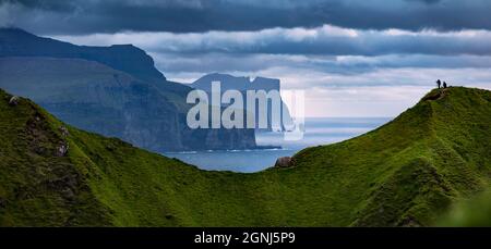 Drammatica scena estiva di popolare attrazione turistica - Risin og Kellingin scogliere, Kallur Lighthouse posizione, Kalsoy isola. Vista panoramica mattutina di Foto Stock