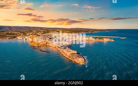 Vista dal drone volante. Emozionante paesaggio urbano serale di Vieste - città costiera nel Parco Nazionale del Gargano con Castello Svevo, Italia, Europa. Mozzafiato Foto Stock