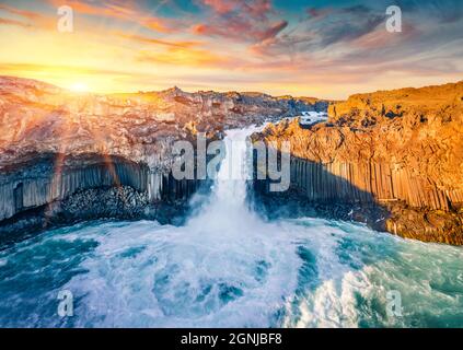 Vista dal drone volante. Tramonto estivo soleggiato sulla cascata Aldeyjarfoss. Gli ultimi raggi di sole cadono sulle pendici del canyon del fiume Skjalfandafljot. Aer Foto Stock