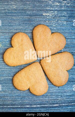 Quattro biscotti allo zenzero sulla superficie di legno grigio invecchiato. Cartolina per san Valentino sfondo giorno. Trifoglio a quattro foglie simbolo di fortuna. Pasticceria per Foto Stock