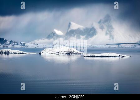 Maestosa scena invernale delle Isole Lofoten con ponte Fredvang sullo sfondo. Dramatik mattina vista della Norvegia, Europa. Catena montuosa nella tempesta di neve. Foto Stock