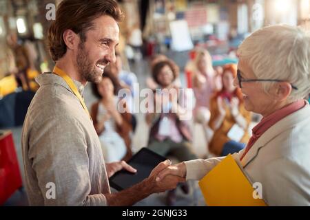 Una donna anziana si congratula con la sua collega per una presentazione ben tenuta per i dipendenti in un'atmosfera piacevole in ufficio Foto Stock