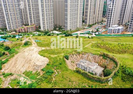 Zhengzhou, Zhengzhou, Cina. 26 settembre 2021. Il 23 settembre 2021, Zhengzhou, Henan, la ''Villa Nail Household' situata in fondo alla fossa nella cintura verde della terza circonvallazione occidentale. Dopo una pioggia pesante, il suolo intorno alla buca crollò. Quasi tutto il primo piano della casa è stato sommerso da limo ed è stato chiamato dai passanti-da ''la famiglia più miserabile del chiodo.'.questa casa è due edifici alti tre piani. È stato circondato da terra e bambù dal 2015. Il proprietario, il signor Zheng, ha detto che la gente ha vissuto qui per generazioni. Non c'è elettricità o acqua, e. Foto Stock