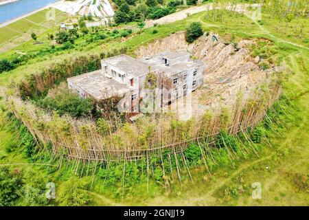 Zhengzhou, Zhengzhou, Cina. 26 settembre 2021. Il 23 settembre 2021, Zhengzhou, Henan, la ''Villa Nail Household' situata in fondo alla fossa nella cintura verde della terza circonvallazione occidentale. Dopo una pioggia pesante, il suolo intorno alla buca crollò. Quasi tutto il primo piano della casa è stato sommerso da limo ed è stato chiamato dai passanti-da ''la famiglia più miserabile del chiodo.'.questa casa è due edifici alti tre piani. È stato circondato da terra e bambù dal 2015. Il proprietario, il signor Zheng, ha detto che la gente ha vissuto qui per generazioni. Non c'è elettricità o acqua, e. Foto Stock