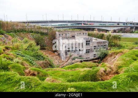 Zhengzhou, Zhengzhou, Cina. 26 settembre 2021. Il 23 settembre 2021, Zhengzhou, Henan, la ''Villa Nail Household' situata in fondo alla fossa nella cintura verde della terza circonvallazione occidentale. Dopo una pioggia pesante, il suolo intorno alla buca crollò. Quasi tutto il primo piano della casa è stato sommerso da limo ed è stato chiamato dai passanti-da ''la famiglia più miserabile del chiodo.'.questa casa è due edifici alti tre piani. È stato circondato da terra e bambù dal 2015. Il proprietario, il signor Zheng, ha detto che la gente ha vissuto qui per generazioni. Non c'è elettricità o acqua, e. Foto Stock