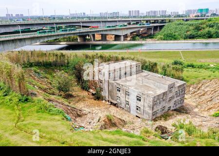 Zhengzhou, Zhengzhou, Cina. 26 settembre 2021. Il 23 settembre 2021, Zhengzhou, Henan, la ''Villa Nail Household' situata in fondo alla fossa nella cintura verde della terza circonvallazione occidentale. Dopo una pioggia pesante, il suolo intorno alla buca crollò. Quasi tutto il primo piano della casa è stato sommerso da limo ed è stato chiamato dai passanti-da ''la famiglia più miserabile del chiodo.'.questa casa è due edifici alti tre piani. È stato circondato da terra e bambù dal 2015. Il proprietario, il signor Zheng, ha detto che la gente ha vissuto qui per generazioni. Non c'è elettricità o acqua, e. Foto Stock