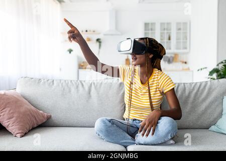 Donna afro-americana che indossa occhiali VR, puntando verso lo spazio delle copie Foto Stock