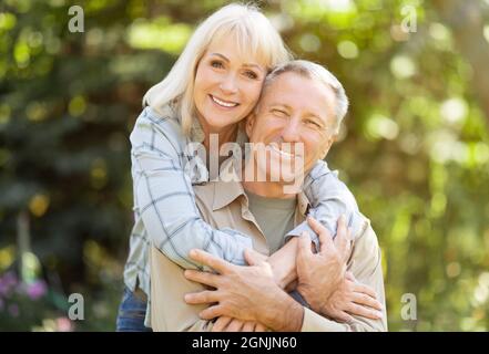 Sposi anziani romantici godendosi il tempo insieme, seduti in giardino al giorno di sole, spazio copia Foto Stock