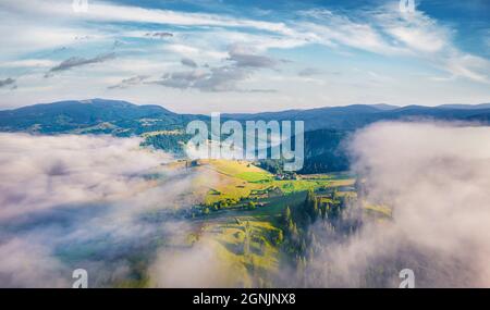 Vista dal drone volante delle montagne carpaziane con enormi spruzza di nebbia sulla valle, Ucraina, Europa. Splendida scena mattutina del villaggio di Stebnyi. Viaggiatori Foto Stock