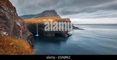 Incredibile scena mattutina della cascata di Mulafossur. Spettacolare vista autunnale del villaggio di Gasadalur, Vagar, Isole Faroe, Danimarca, Europa. Viaggi conce Foto Stock