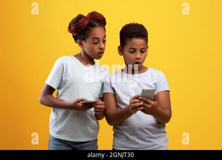 Scioccato fratello nero e sorella utilizzando smartphone Foto Stock