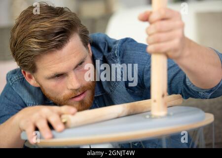 uomo carpentiere con cacciavite a mano che lavora nella riparazione di mobili Foto Stock