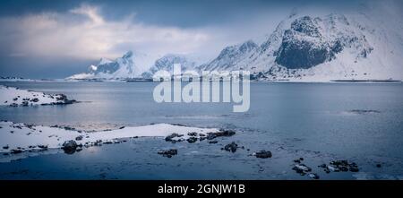 Vista panoramica invernale delle Isole Lofoten con ponte Fredvang sullo sfondo. Dramatik scena mattutina della Norvegia, Europa. Catena montuosa nella tempesta di neve Foto Stock