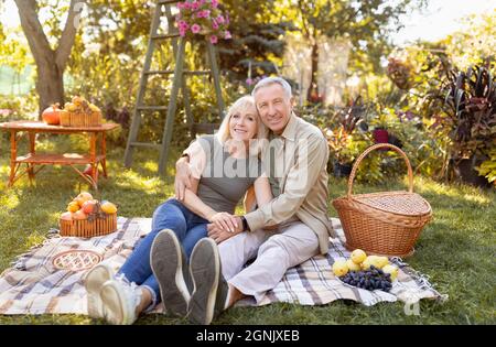 Felice coppia anziana riposo nel parco autunnale, avendo pic-nic e sorridendo a macchina fotografica, spazio copia Foto Stock