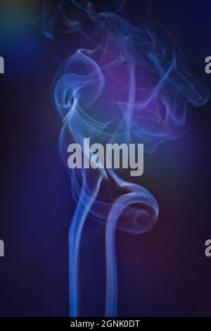 Un colpo di fumo verticale con una retroilluminazione colorata e una nota blu Foto Stock
