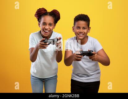 Gioioso fratello nero e sorella che tiene i joystick Foto Stock