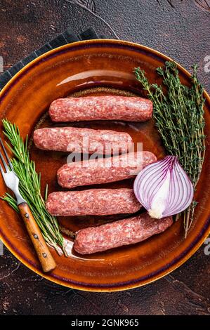 Kofta cruda carne kebabs salsicce su un piatto con erbe. Sfondo scuro. Vista dall'alto Foto Stock