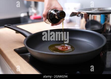 La donna versa l'olio d'oliva in una padella calda Foto Stock