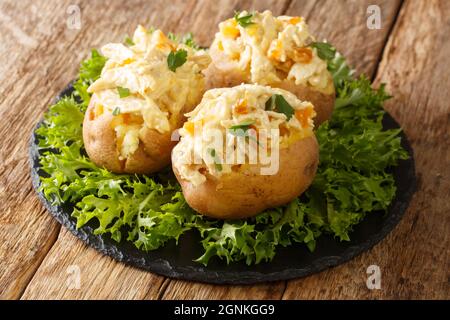 Patate al forno inglesi condite con insalata di pollo coronata da primo piano su un tavolo di ardesia. Orizzontale Foto Stock