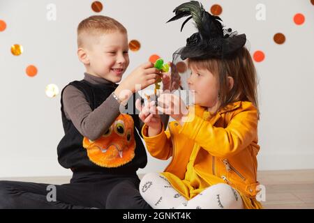 Carino bambina e ragazzo in costume strega e ragno giocare a casa. Festa di Halloween Foto Stock