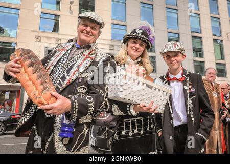 St Mary-le-Bow, Londra, Regno Unito. 26 settembre 2021. Un re Pearly con il suo Principe e la Principessa porta un pane al servizio di raccolta del Costermonger. Pearly Kings e Queens celebrano il loro festival annuale del raccolto con il servizio di raccolta del Costermonger presso la chiesa di St Mary-le-Bow. Poiché le solite celebrazioni a Guildhall Yard dovevano essere cancellate, le Perle si incontrano e salutano gli amici e il pubblico fuori dalla chiesa prima e dopo il servizio del suo anno. Credit: Imagplotter/Alamy Live News Foto Stock