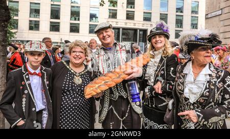 St Mary-le-Bow, Londra, Regno Unito. 26 settembre 2021. Un re di Pearly con il suo principe e la principessa porta una pagnotta di offerta di pane al servizio di raccolta del Costermonger. Pearly Kings e Queens celebrano il loro festival annuale del raccolto con il servizio di raccolta del Costermonger presso la chiesa di St Mary-le-Bow. Poiché le solite celebrazioni a Guildhall Yard dovevano essere cancellate, le Perle si incontrano e salutano gli amici e il pubblico fuori dalla chiesa prima e dopo il servizio del suo anno. Credit: Imagplotter/Alamy Live News Foto Stock