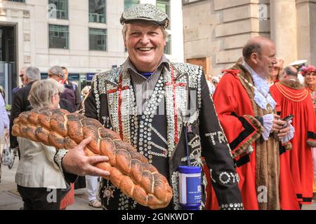 St Mary-le-Bow, Londra, Regno Unito. 26 settembre 2021. Un re di Pearly con il suo principe e la principessa porta una pagnotta di offerta di pane al servizio di raccolta del Costermonger. Pearly Kings e Queens celebrano il loro festival annuale del raccolto con il servizio di raccolta del Costermonger presso la chiesa di St Mary-le-Bow. Poiché le solite celebrazioni a Guildhall Yard dovevano essere cancellate, le Perle si incontrano e salutano gli amici e il pubblico fuori dalla chiesa prima e dopo il servizio del suo anno. Credit: Imagplotter/Alamy Live News Foto Stock