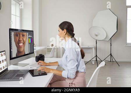 Fotografo che modifica le immagini su un computer mentre lavora in un moderno studio fotografico Foto Stock