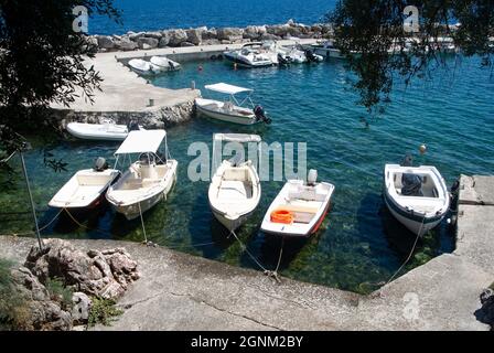 Corfù isola Grecia Nissaki vllage piccolo porto appartato con piccole barche a motore ormeggiate in un molo aspetto paesaggistico Foto Stock