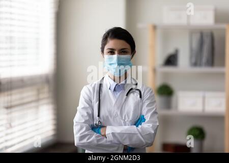 Felice medico indiano femmina GP in maschera facciale, guanti protettivi Foto Stock