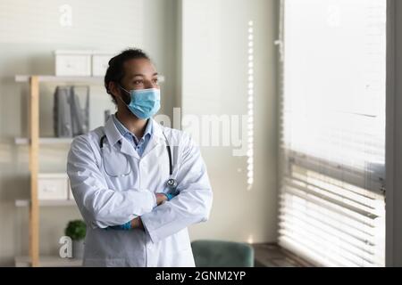 Medico serio maschio in maschera facciale, cappotto bianco con stetoscopio Foto Stock