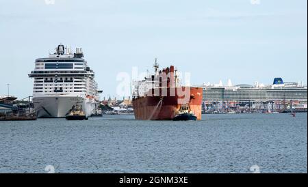 Southampton, Inghilterra, Regno Unito, 2021. Tugs scorta un portarinfuse che naviga vuoto nel porto di Southampton. Passando accanto alle navi da crociera. Foto Stock