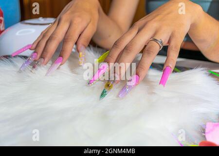 primo piano di mano con unghie molto lunghe con decorazioni diverse Foto Stock