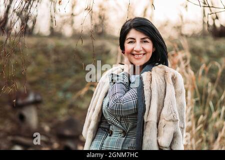 Donna moderna di mezza età in pelliccia di cappotto, sorridente Foto Stock