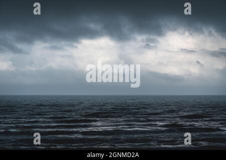 Malinconico blu scuro con argento che splende onde ruvide durante la tempesta Foto Stock