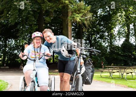 Hakendover, Brabante fiammingo, Belgio - 09 20 2021: Donna di 39 anni con sindrome Down e suo fratello felice in bicicletta Foto Stock