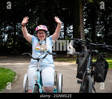 Hakendover, Brabante fiammingo, Belgio - 09 20 2021: Donna di 39 anni con sindrome Down sulla strada con il suo triciclo Foto Stock