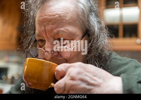 Nonna bere caffè a casa Foto Stock