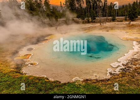 Sorgenti termali nel parco nazionale di Yellowstone, Wyoming. Cielo al tramonto con vapore e centro piscina blu. Foto Stock