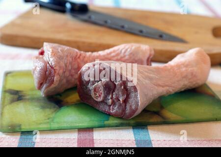 Due tamburi in tacchino crudi sul tagliere di vetro Foto Stock