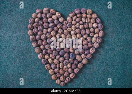 Mostrando la forma del cuore fatta con frutta secca delle noci che è molto buono per il controllo di malattia di cuore, concetto Foto Stock
