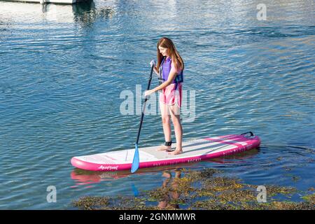 Giovane donna pagaia a Portrush Harbour, Portrush (Port Rois), County Antrim, Irlanda del Nord, Regno Unito Foto Stock